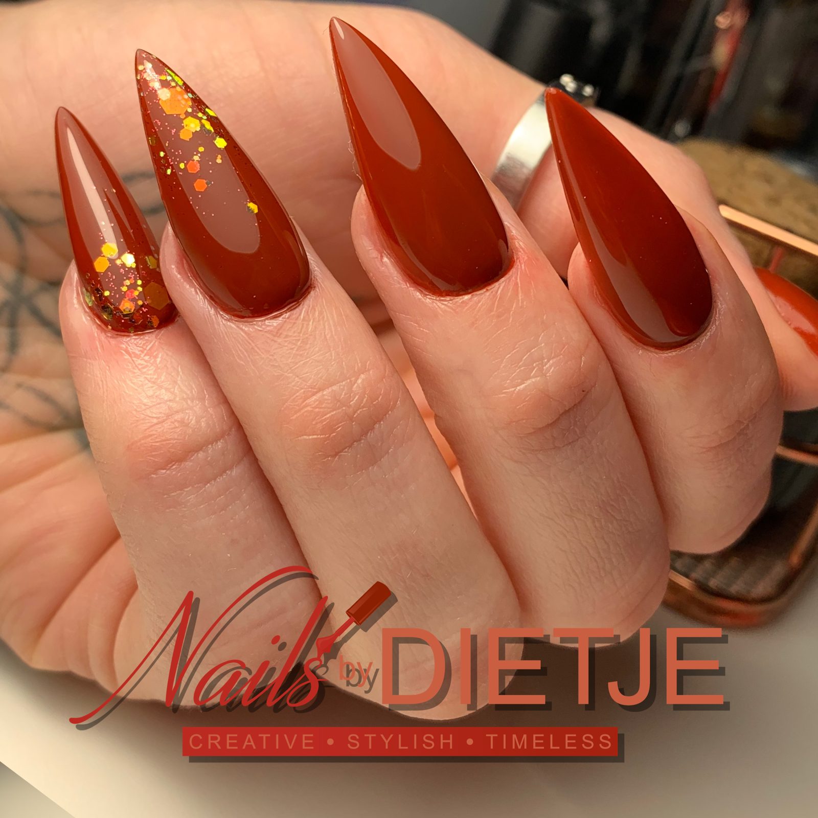 Dieprode stiletto nagels met oranje glitteraccenten