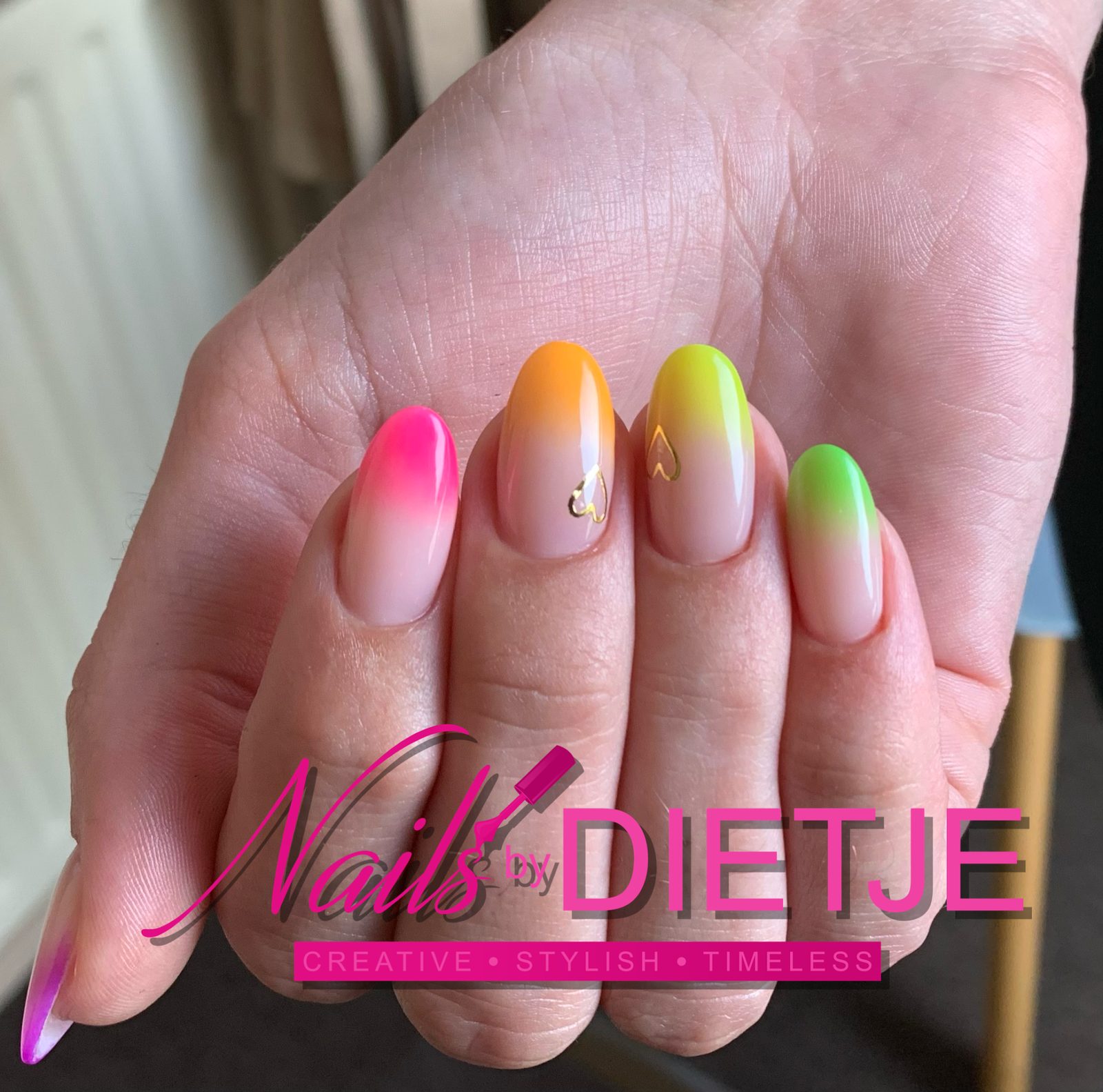 Neon ombre nagels van roze naar oranje en groen, met kleine gouden hartjes